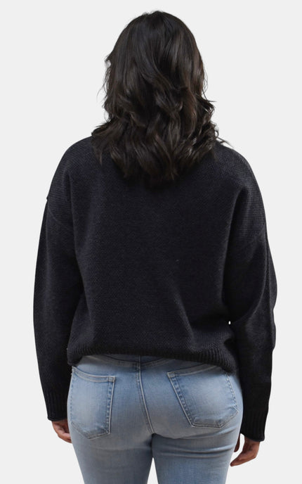 Elegant black mock neck sweater styled with denim for a timeless look.