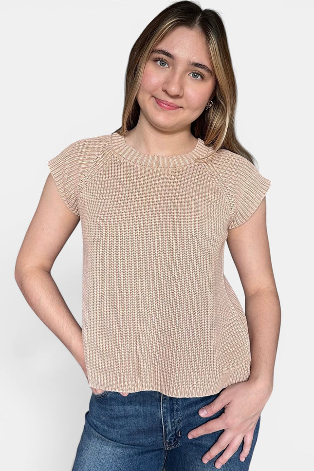 Beige ribbed short-sleeve top and blue jeans, standing against a light gray studio background.