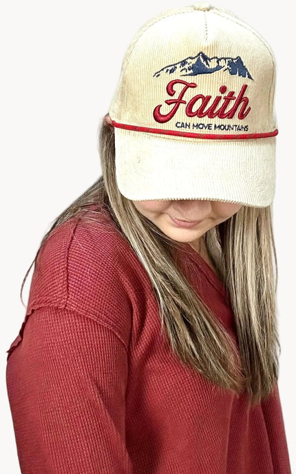 Person wearing a cap with 'Faith can move mountains' text on a plain background