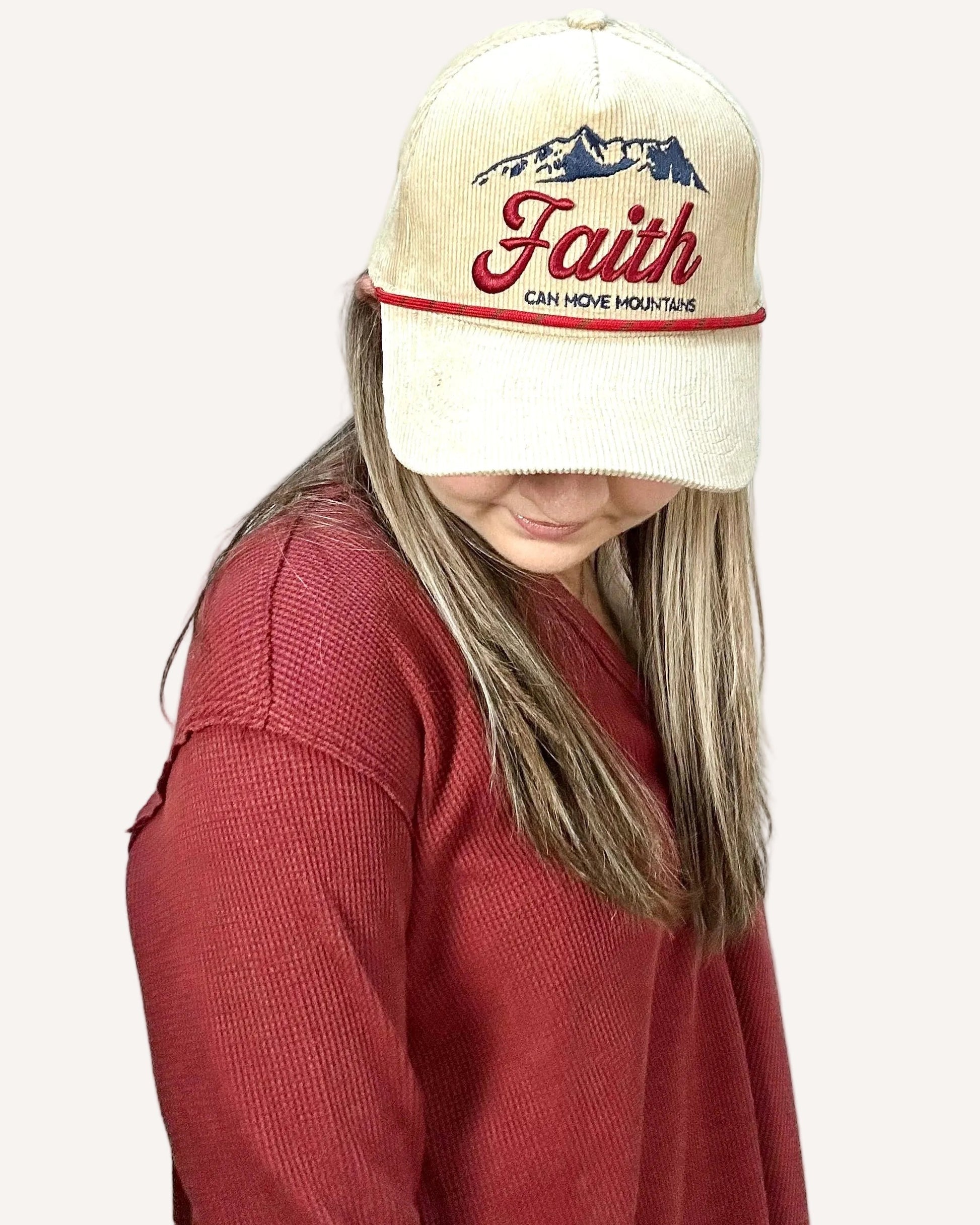 Person wearing a cap with 'Faith can move mountains' text on a plain background