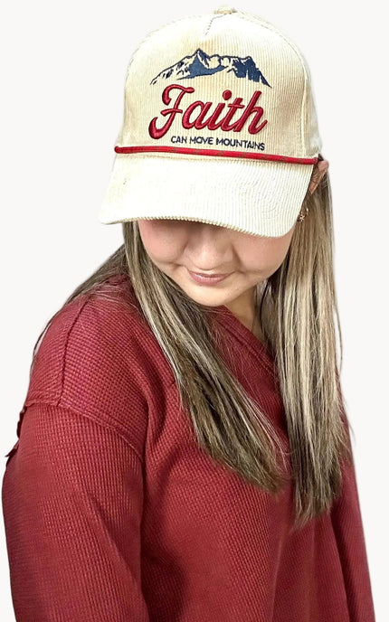 Person wearing a cap with 'Faith Can Move Mountains' text on a plain background