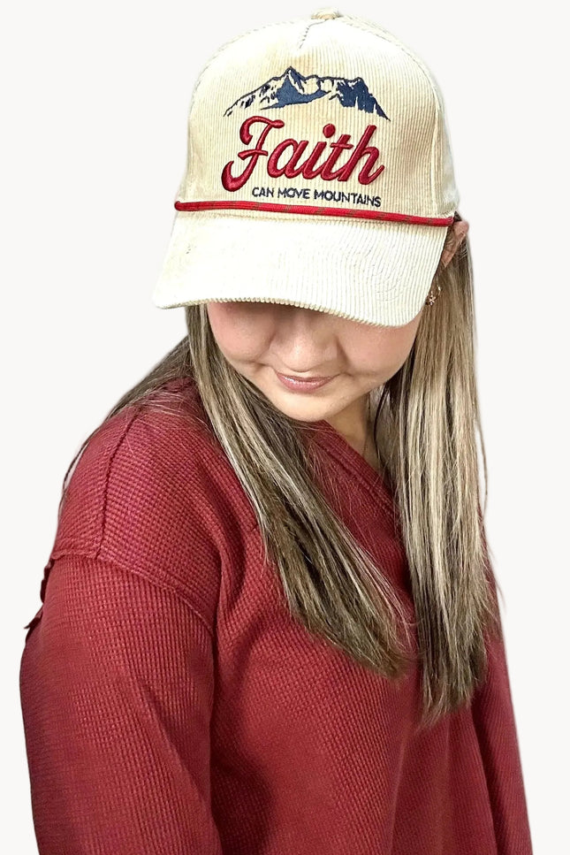 Person wearing a cap with 'Faith Can Move Mountains' text on a plain background
