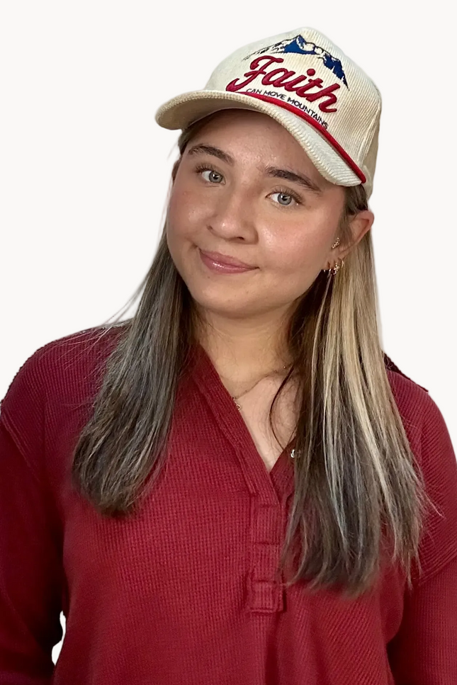 Woman wearing a red shirt and a cap with 'Faith' text on a white background