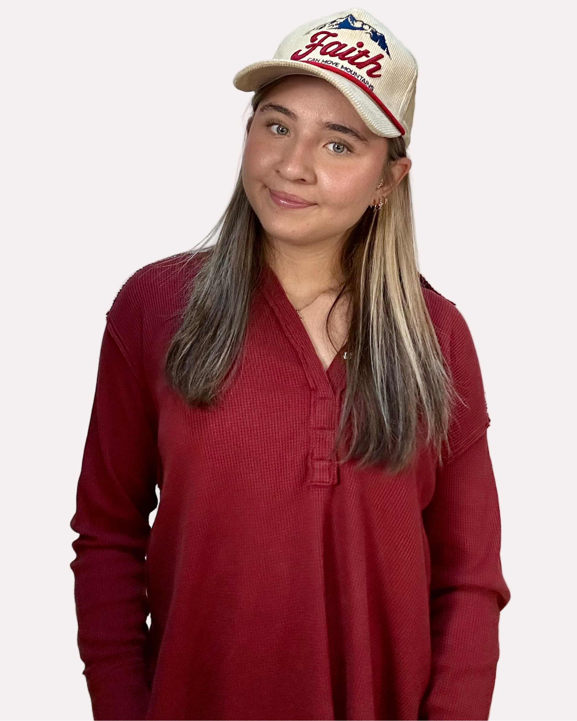 Woman wearing a red shirt and a cap with 'Faith' text on a white background