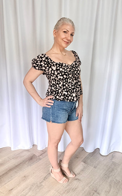 Side view of women's floral sweetheart top with elastic puff sleeves and flowy rayon fabric.