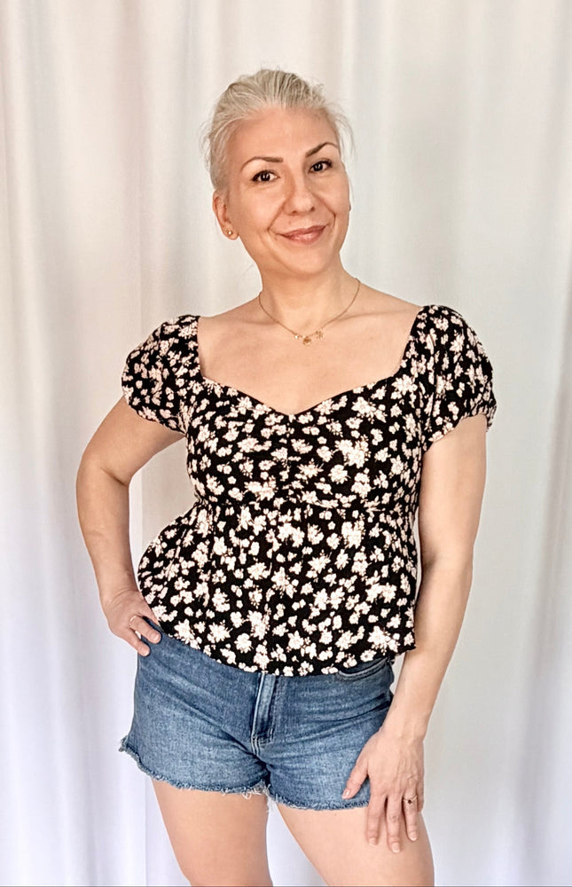 Front view of floral print blouse with puff sleeves and versatile on or off shoulder styling.