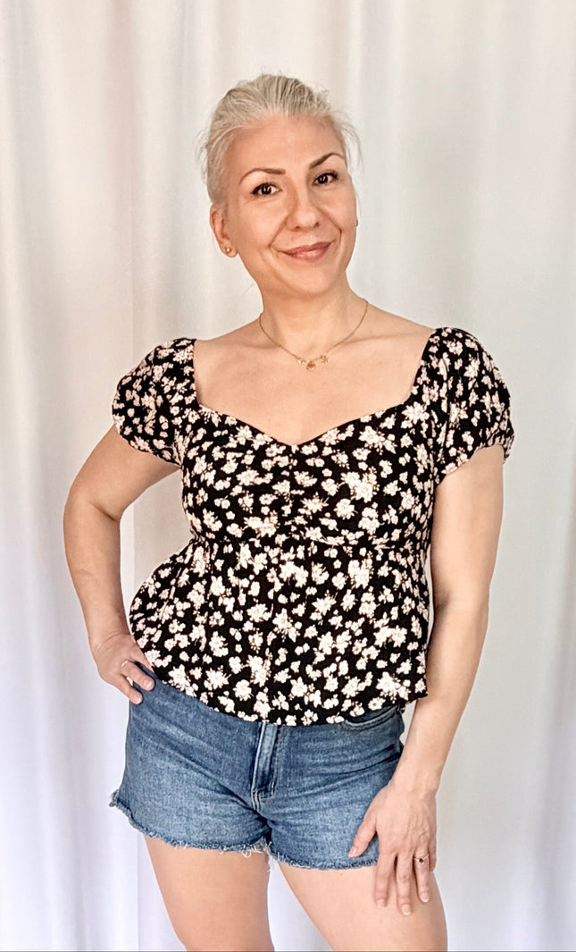 Front view of floral print blouse with puff sleeves and versatile on or off shoulder styling.
