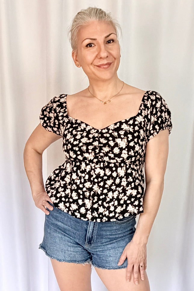 Front view of floral print blouse with puff sleeves and versatile on or off shoulder styling.