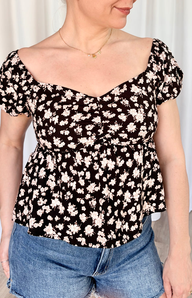 Close up of front view romantic floral top with delicate puff sleeves and soft feminine floral pattern.