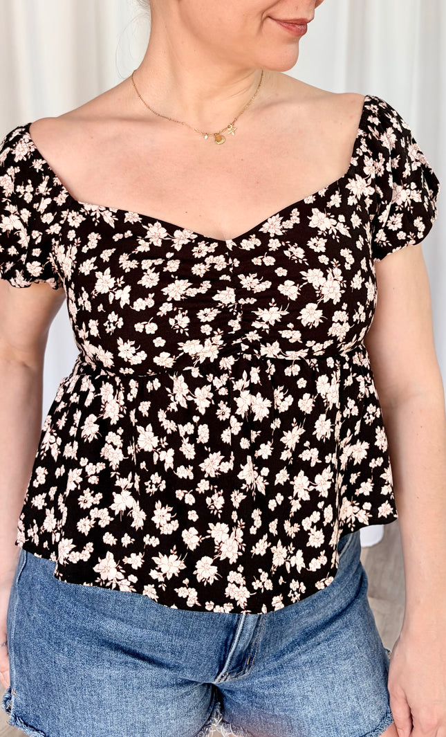 Close up of front view romantic floral top with delicate puff sleeves and soft feminine floral pattern.