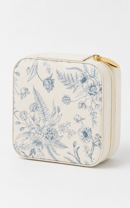 A square cream-colored zippered pouch featuring a blue floral toile de Jouy pattern, with a gold zipper pull, shown on a clean white background.