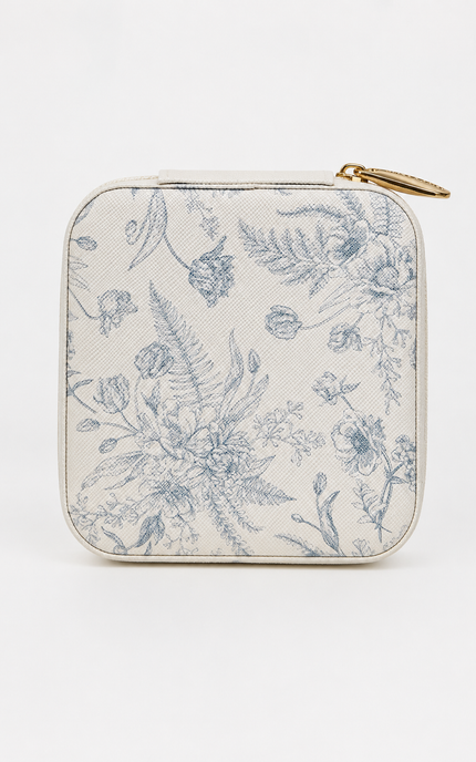 A small zippered pouch with rounded corners, featuring a blue floral toile de Jouy pattern on a cream-colored textured background, finished with a gold-tone zipper pull.