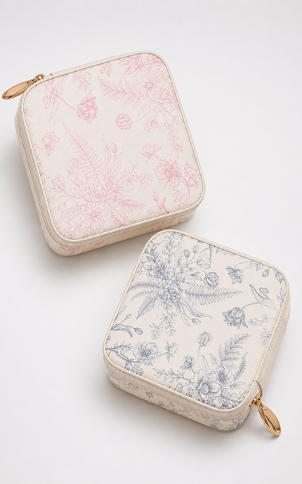 Two square zippered pouches with rounded corners on a light gray background. The top pouch is cream with a pink botanical toile pattern and a gold zipper pull.