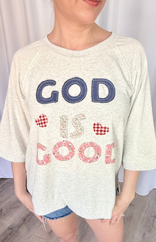 A close-up shot of the unique, vintage-inspired "God is Good" statement patchwork, highlighting the texture of the lettering against the soft French terry fabric.