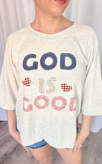 A close-up shot of the unique, vintage-inspired "God is Good" statement patchwork, highlighting the texture of the lettering against the soft French terry fabric.