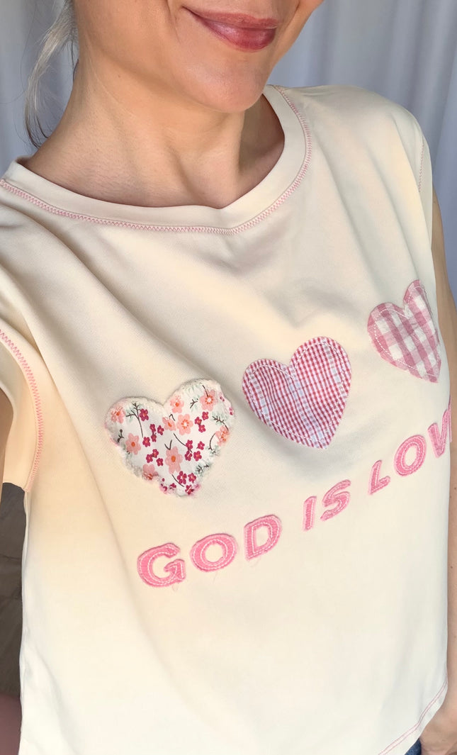 Close-up of patchwork lettering and colorful heart accents on a faith-inspired top.