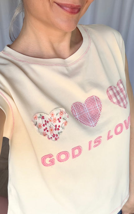 Close-up of patchwork lettering and colorful heart accents on a faith-inspired top.