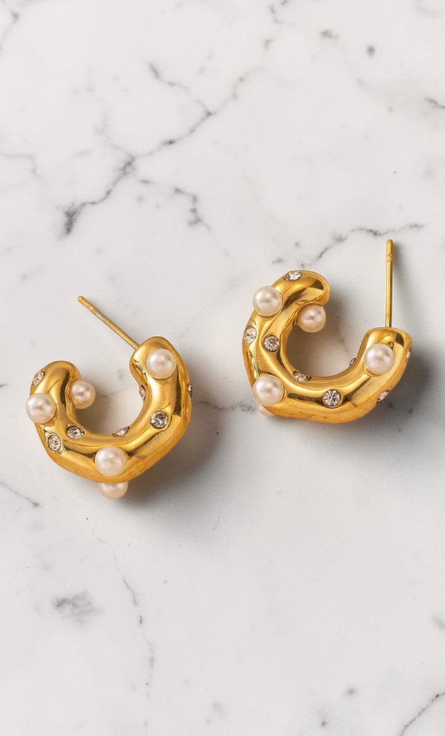 Gold hoop earrings with pearls on a marble surface