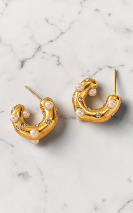 Gold hoop earrings with pearls on a marble surface