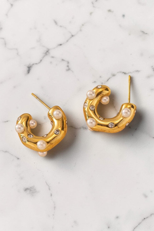 Gold hoop earrings with pearls on a marble surface