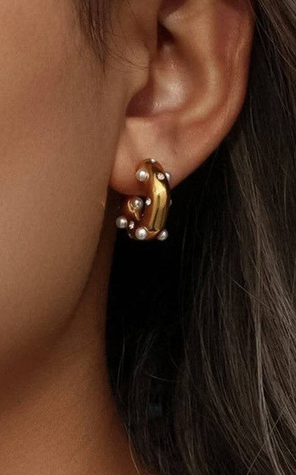Close-up of an ear wearing a gold earring with pearls.