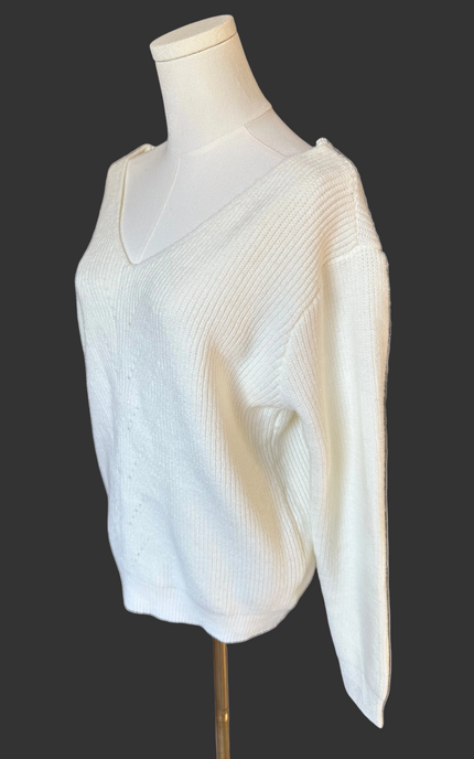 Off-white ribbed sweater with lace-trim V-neckline and oversized bow detail draping down the back, photographed on a Soft Linen background for Justyna Grace Boutique.
