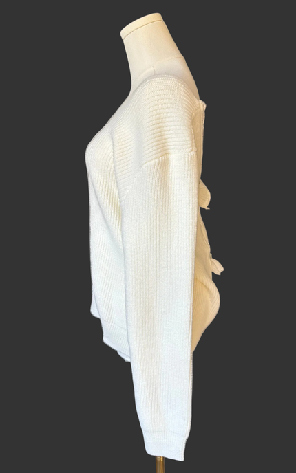 Off-white ribbed sweater with lace-trim V-neckline and oversized bow detail draping down the back, photographed on a Soft Linen background for Justyna Grace Boutique.