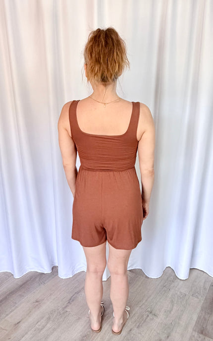 Back view of a hazelnut romper featuring a sleeveless design and shirred waist.