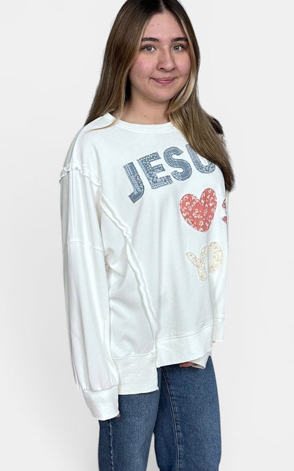 Woman wearing a "Jesus Loves You" mineral wash French terry sweatshirt with blue jeans