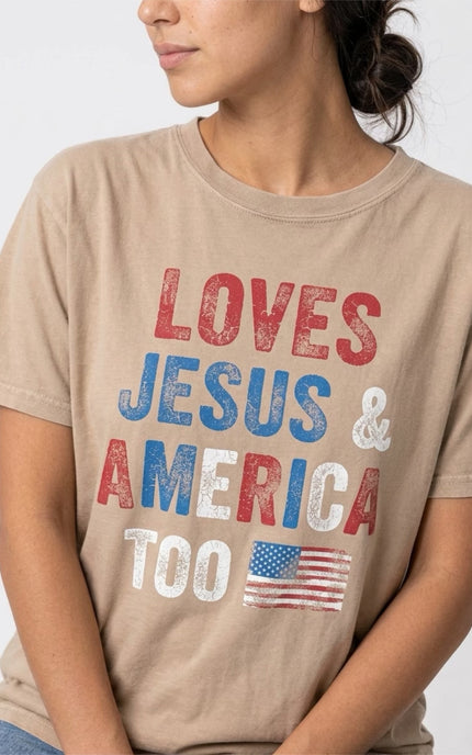 Person wearing a beige t-shirt with 'LOVES JESUS & AMERICA TOO' text and an American flag.