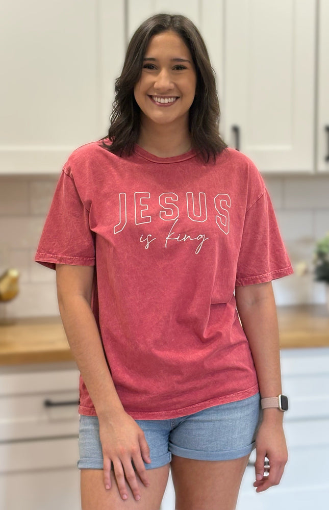 Red mineral-wash “Jesus Is King” graphic tee with relaxed unisex fit and vintage garment-dyed finish.