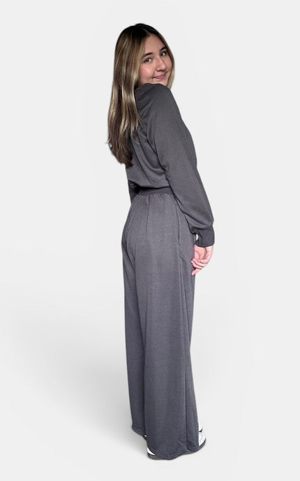 Side view of a soft stretch knit jumpsuit in dark gray with a wide neckline.