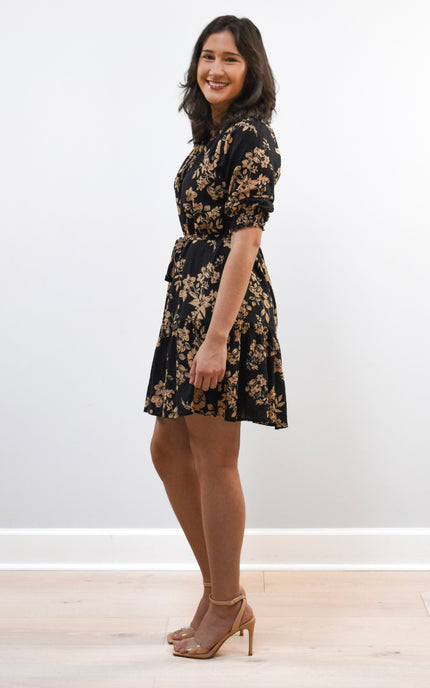 Woman wearing a black floral dress against a white background