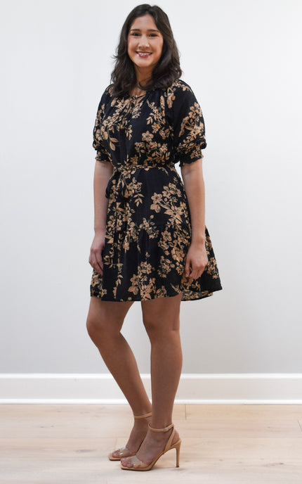 Kelly Mini Dress on soft linen background, featuring a ruffle neckline with tie and lightweight cotton–rayon fabric.
