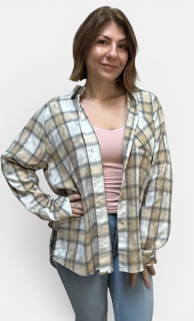 A woman modeling a long-sleeve plaid button-up shirt in beige, white, and gray, worn open over a light pink tank top and blue jeans, against a plain light gray background.