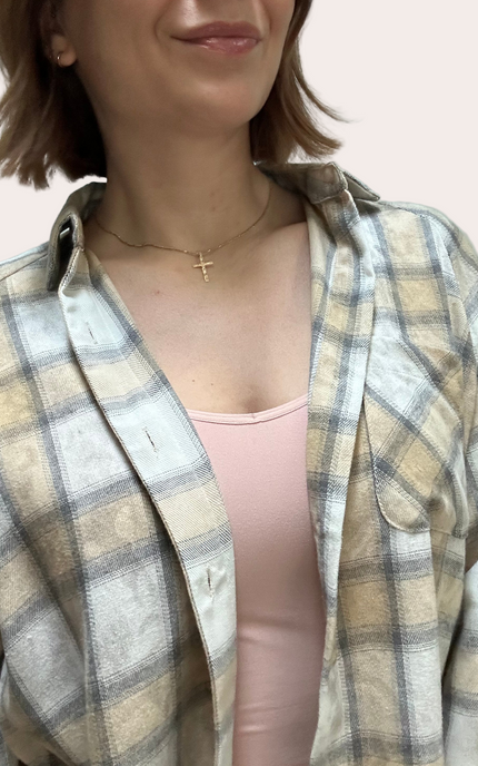 Person wearing a plaid shirt over a pink top with a plain background