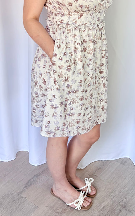 Close-up of the floral print and front tie detail on a lavender mini dress with pockets.