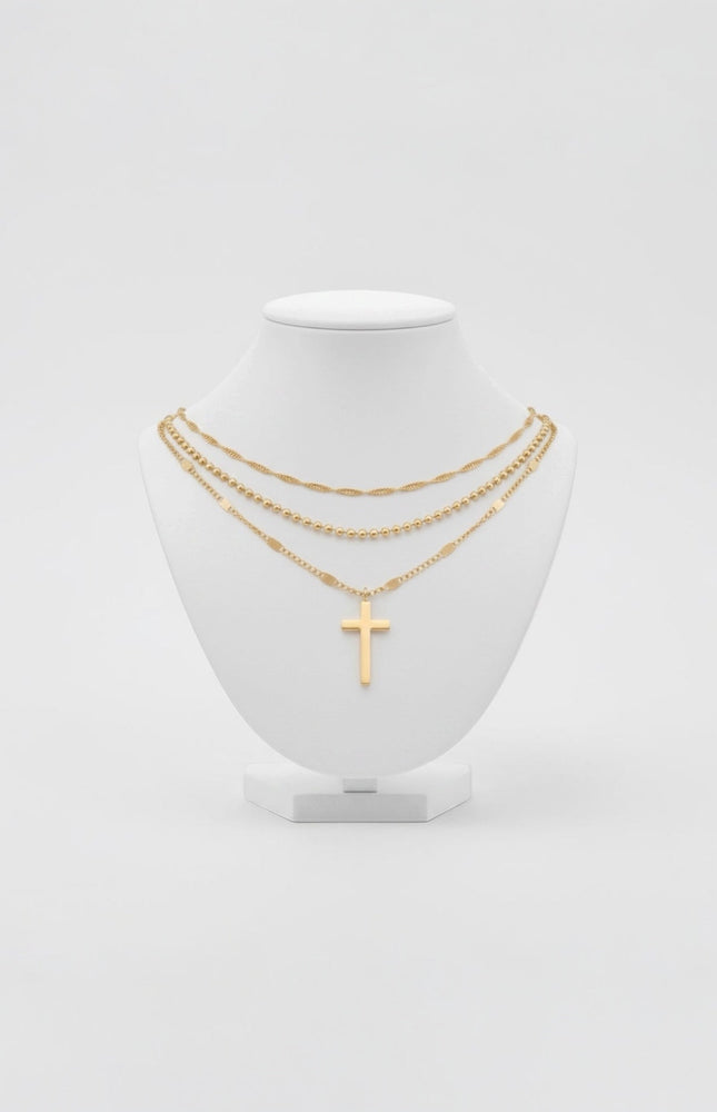 Triple‑chain gold necklace with cross pendant displayed on neutral background, waterproof stainless steel.