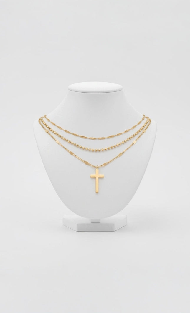Triple‑chain gold necklace with cross pendant displayed on neutral background, waterproof stainless steel.