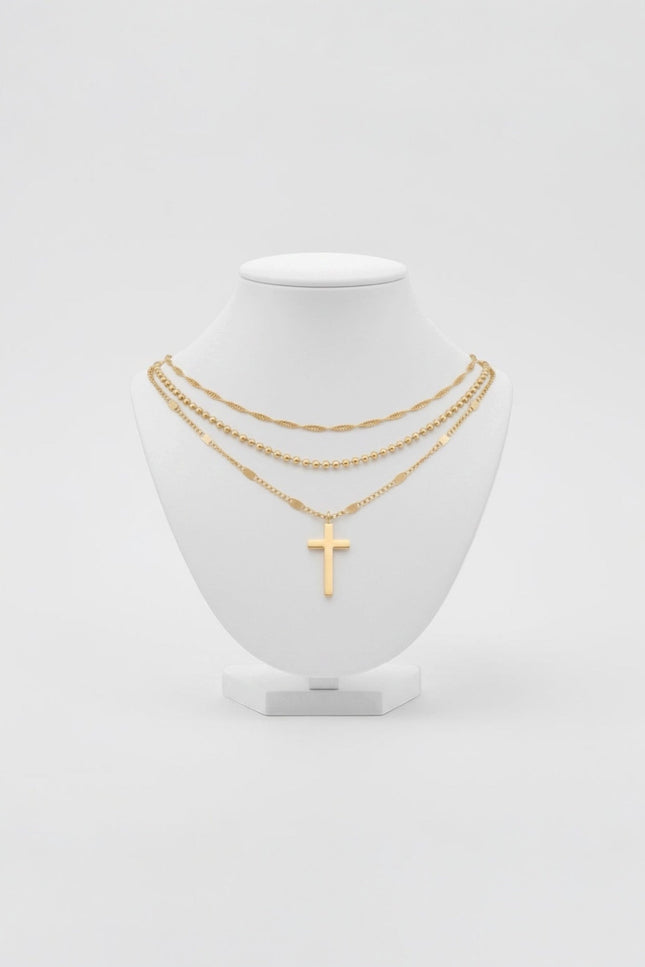 Triple‑chain gold necklace with cross pendant displayed on neutral background, waterproof stainless steel.