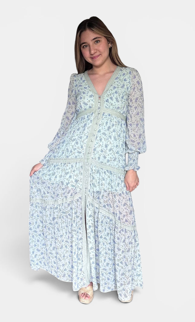 Long-sleeved maxi dress with a light blue and white floral pattern, standing against a plain light gray studio background.