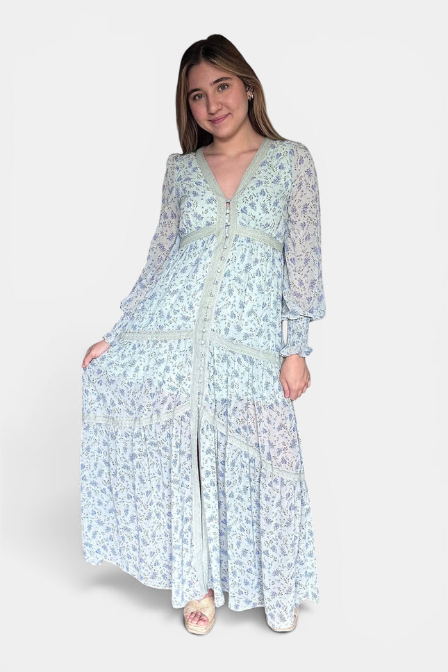 Long-sleeved maxi dress with a light blue and white floral pattern, standing against a plain light gray studio background.