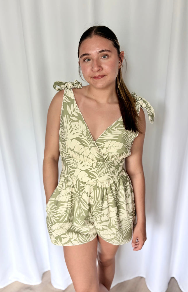 Front view of dusty sage tropical print romper with overlapping V‑neckline and relaxed short silhouette.
