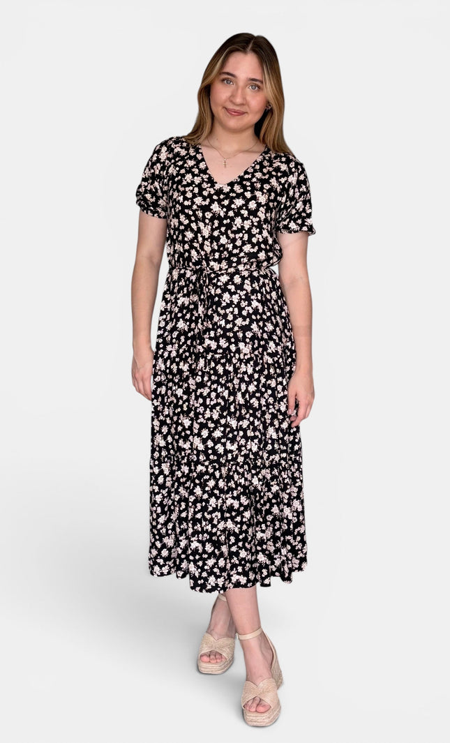 Short-sleeve midi dress with a black background and a dense white floral pattern, paired with beige platform sandals, against a plain light gray studio background.