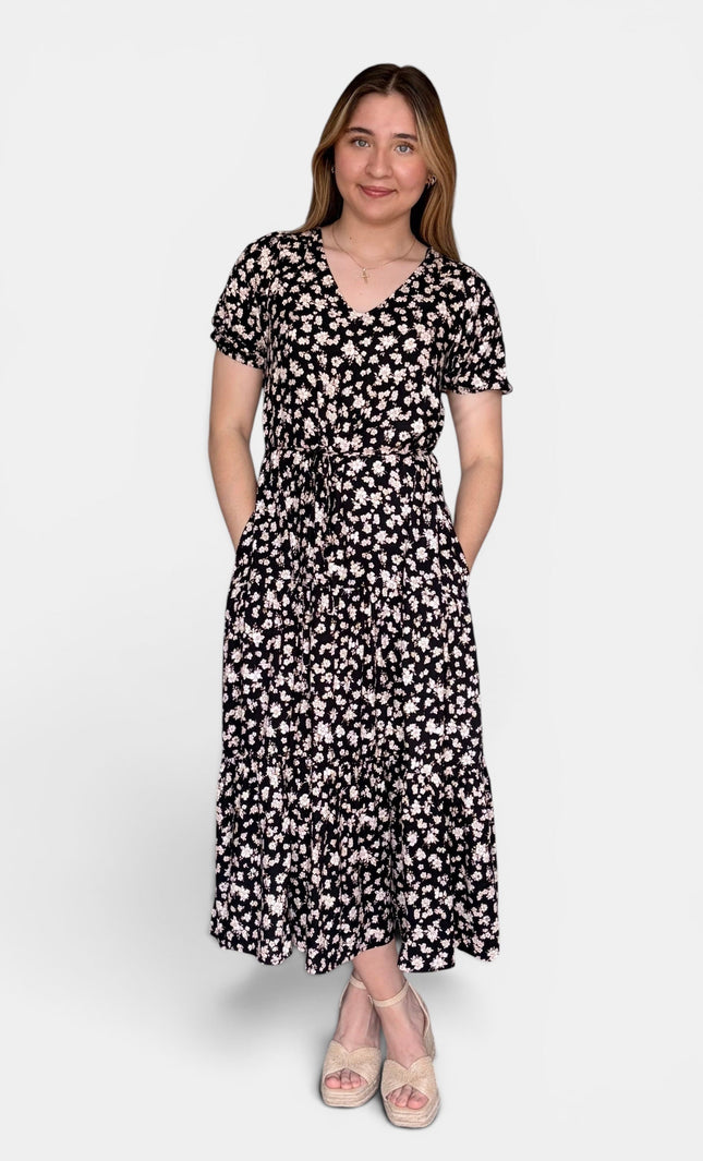 Short-sleeve midi dress with a black and white floral pattern, standing against a light gray studio background.