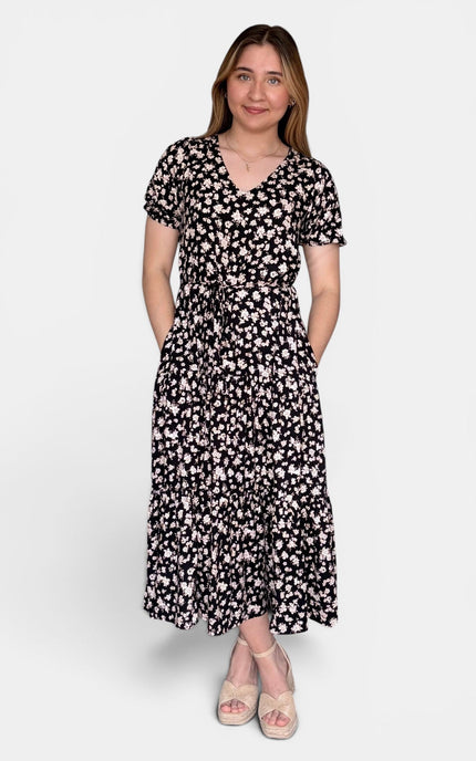 Short-sleeve midi dress with a black and white floral pattern, standing against a light gray studio background.