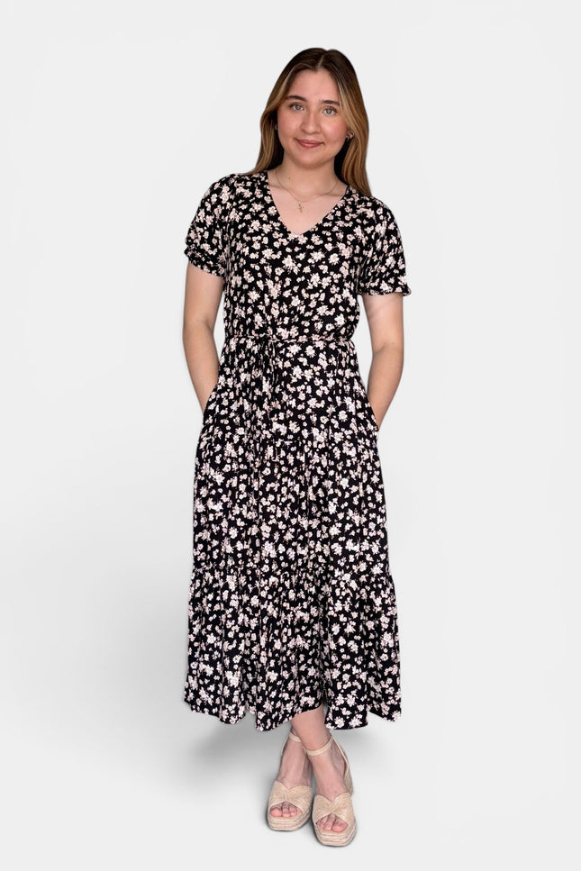Short-sleeve midi dress with a black and white floral pattern, standing against a light gray studio background.