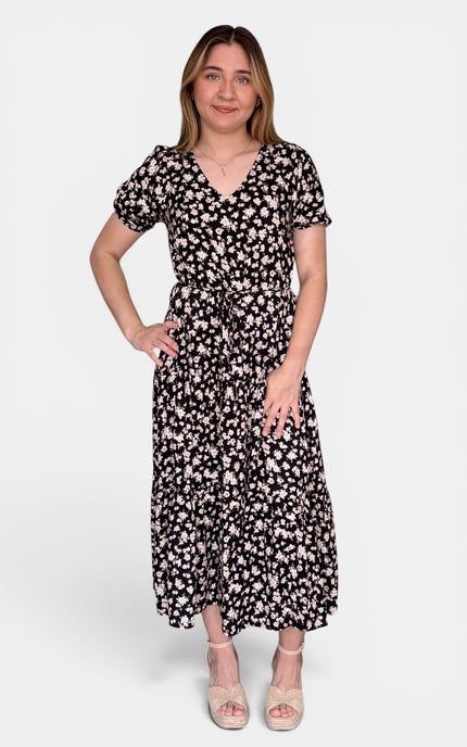 Short-sleeve midi dress with a black base and a white floral pattern, paired with beige platform sandals, against a light gray studio background.