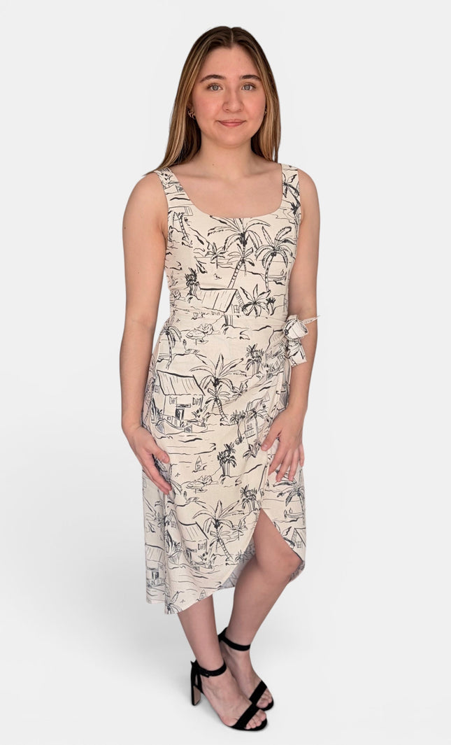 A sleeveless midi dress with a black line-art tropical and beach-themed print on a warm cream background, paired with black strappy heels, against a light gray studio background.
