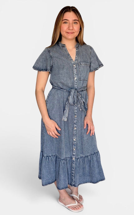 A light blue tencel denim midi dress with short flutter sleeves, a button-up front, a tie waist, and a ruffled hem, paired with white flip-flop sandals against a light gray background.